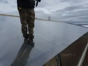 worker on top of a greenhouse